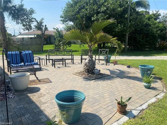 a view of a patio with table and chairs potted plants and palm trees