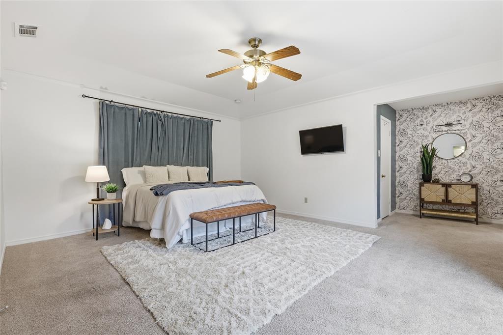 823 Ridgecrest Circle Denton, TX 76205 - Photo 17 of 40 Spacious room featuring carpeting, ceiling fan, accent wall with patterned wallpaper, and a wall-mounted television