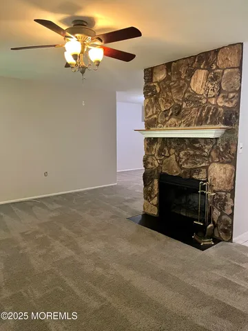 a view of a livingroom with a fireplace and a chandelier fan