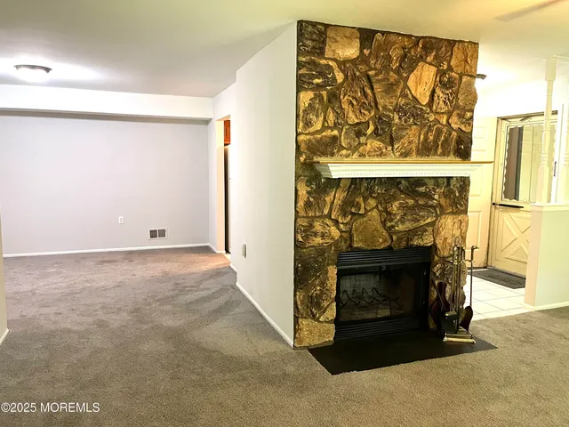 a view of an empty room with wooden floor and a fireplace