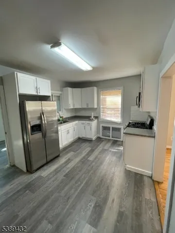 a kitchen with a refrigerator a stove top oven a sink a counter space and cabinets