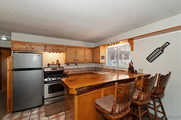 a kitchen with stainless steel appliances granite countertop a stove a refrigerator and a sink with wooden floors