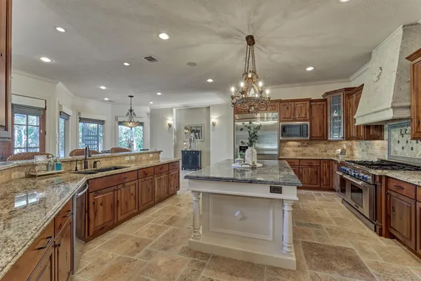a kitchen with stainless steel appliances granite countertop a stove top oven a sink dishwasher a dining table and chairs