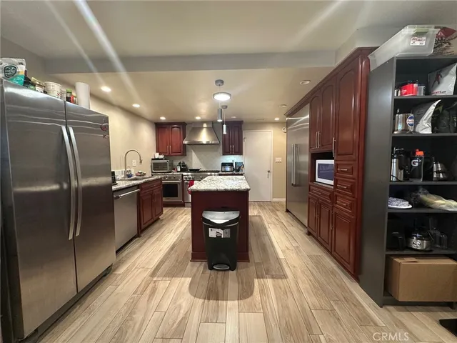 a kitchen with stainless steel appliances granite countertop a refrigerator a stove and a wooden floors