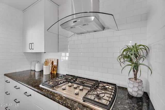 a kitchen with a stove a sink a chimney and cabinets