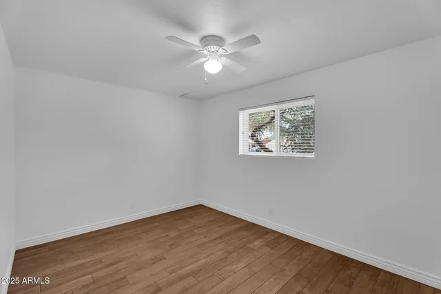 an empty room with wooden floor and ceiling fan