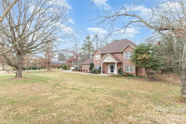 a view of big yard next to a house with large trees