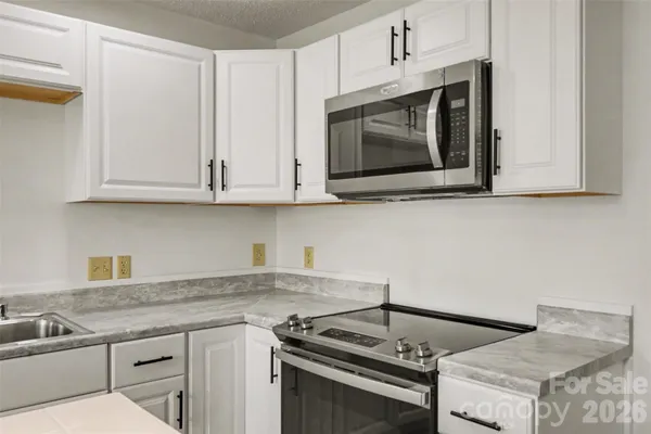 a kitchen with granite countertop a stove top oven microwave and cabinets