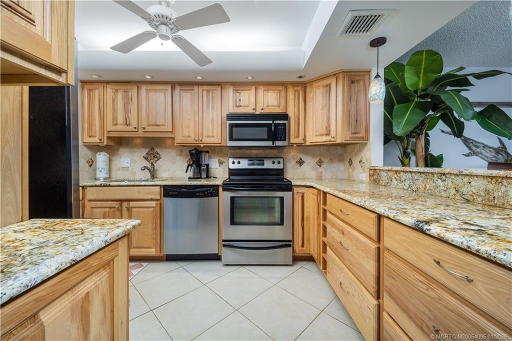 3100 Southeast Pruitt Road, Unit G205 Port St. Lucie, FL 34952 - Photo 8 of 29 a kitchen with granite countertop a stove a sink and a microwave