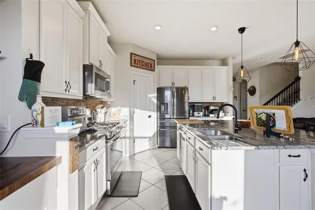 a kitchen with stainless steel appliances granite countertop a sink and a refrigerator