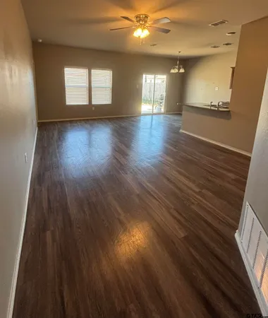 an empty room with wooden floor and windows
