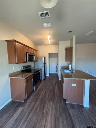 a kitchen with stainless steel appliances wooden floors wooden cabinets and refrigerator