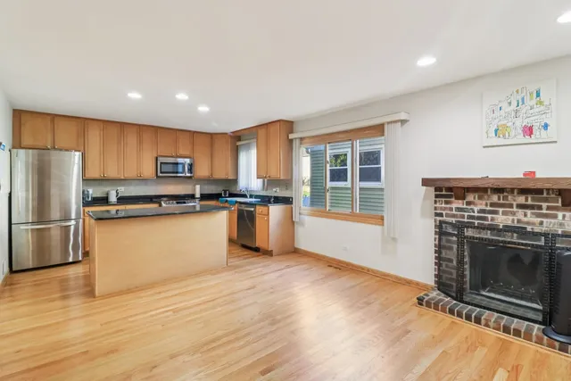 a kitchen with granite countertop stainless steel appliances a refrigerator cabinets and wooden floor