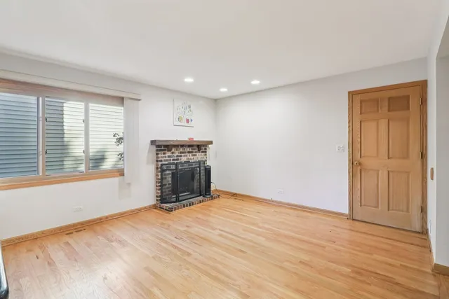 a view of empty room with wooden floor and fireplace