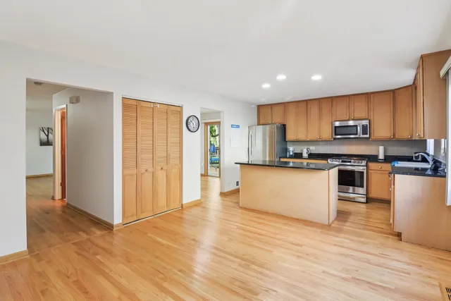 a kitchen with stainless steel appliances granite countertop a stove top oven a refrigerator a sink and dishwasher with wooden floor