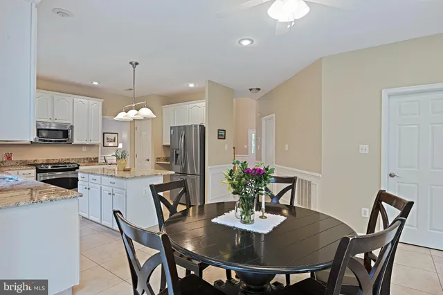a kitchen with stainless steel appliances granite countertop a sink dishwasher and a refrigerator with wooden floor