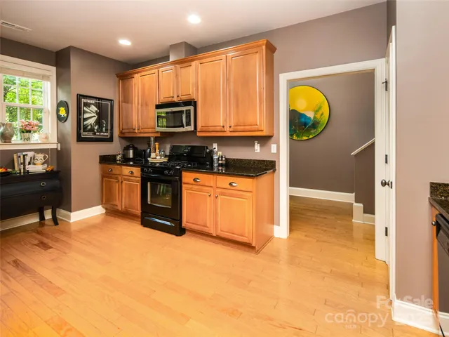 a kitchen with stainless steel appliances granite countertop a stove a sink and a microwave