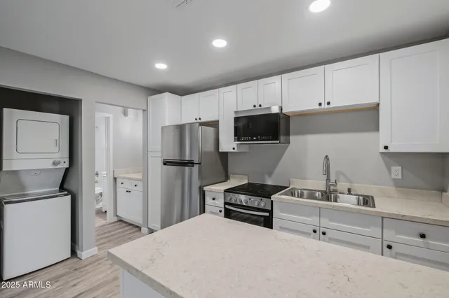 a kitchen with a refrigerator a stove and white cabinets