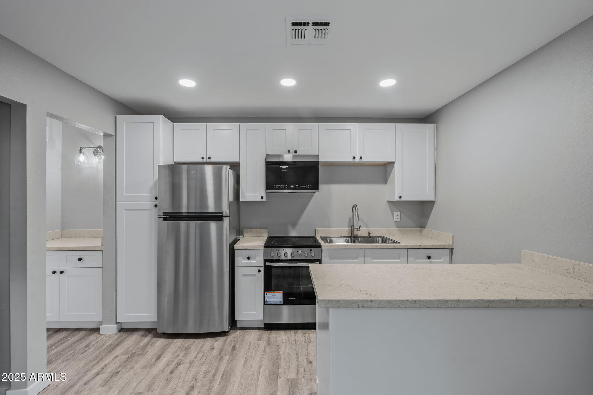 1940 West Amelia Avenue, Unit 1942 5 Phoenix, AZ 85015 - Photo 12 of 18 a kitchen with a refrigerator a stove and white cabinets