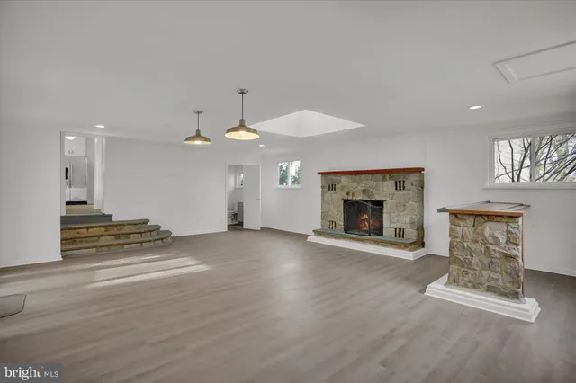 an empty room with windows and fireplace