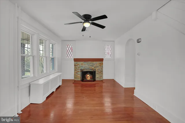 a view of a livingroom with a fireplace a ceiling fan and windows