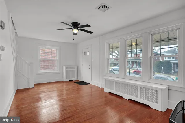a view of empty room with wooden floor and fan