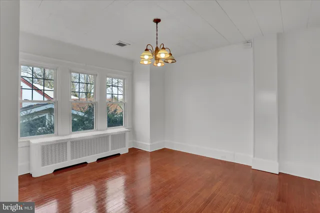 a view of an empty room with wooden floor and windows