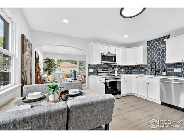 a kitchen with kitchen island granite countertop a stove a sink a refrigerator dining table and chairs with wooden floor