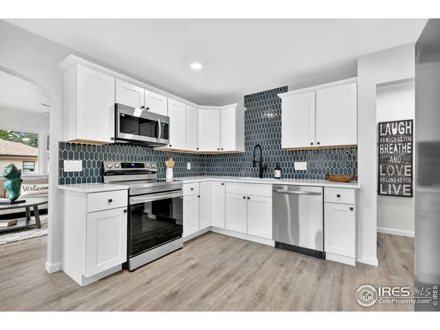 a kitchen with kitchen island granite countertop a stove top oven a sink dishwasher and a refrigerator with wooden floor