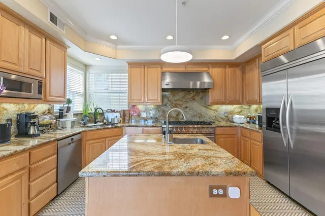 a kitchen with stainless steel appliances granite countertop a sink a stove and a refrigerator