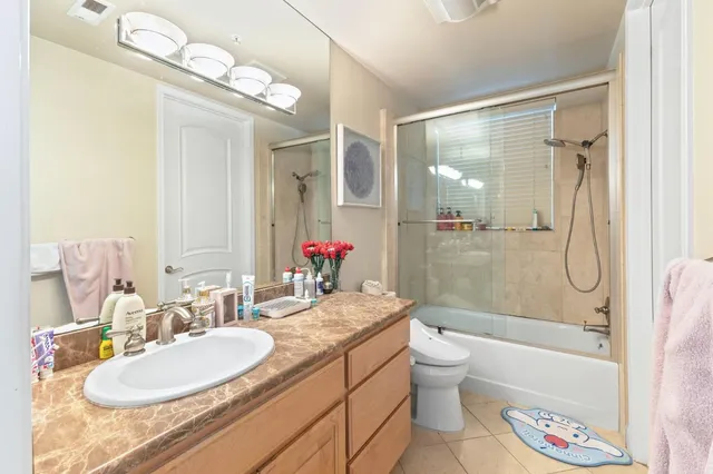 a bathroom with a granite countertop sink a toilet a mirror and shower