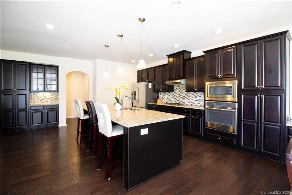 2279 Drake Mill Lane Southwest Concord, NC 28025 - Photo 15 of 40 a kitchen with kitchen island granite countertop wooden floors and stainless steel appliances
