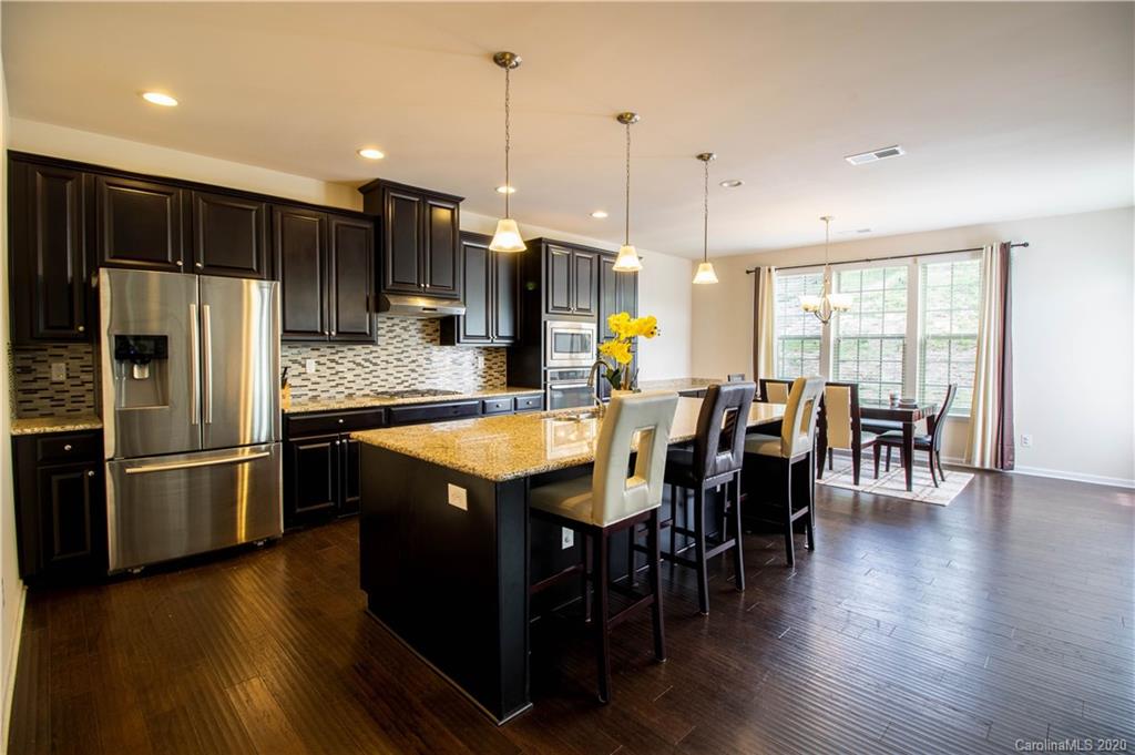2279 Drake Mill Lane Southwest Concord, NC 28025 - Photo 18 of 40 a kitchen with stainless steel appliances granite countertop a refrigerator a stove a sink a dining table and chairs with wooden floor