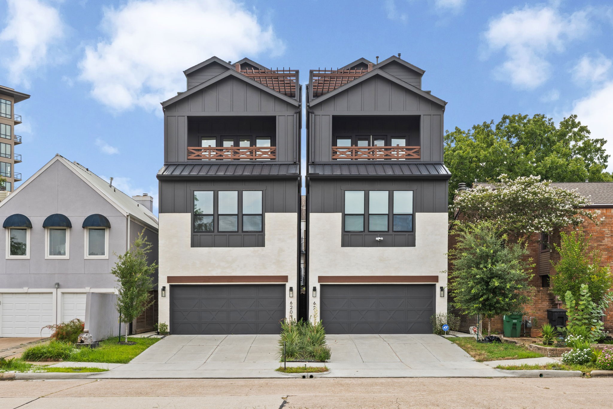 Sophisticated modern exterior with sleek two-tone finishes, private driveway, balcony, and rooftop terrace.