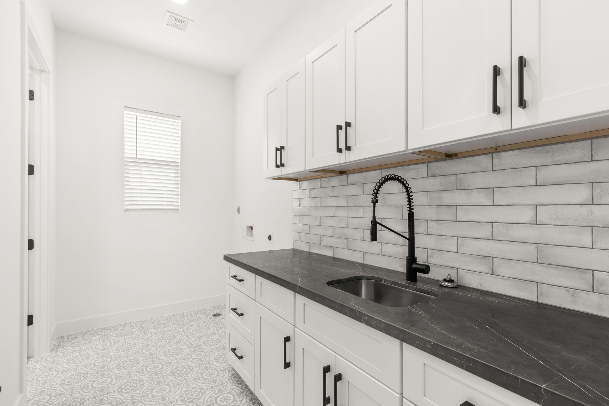 6209 Westcott Street Houston, TX 77007 - Photo 12 of 29 Spacious laundry room with custom cabinetry, designer backsplash, and generous counter space for folding and organization.