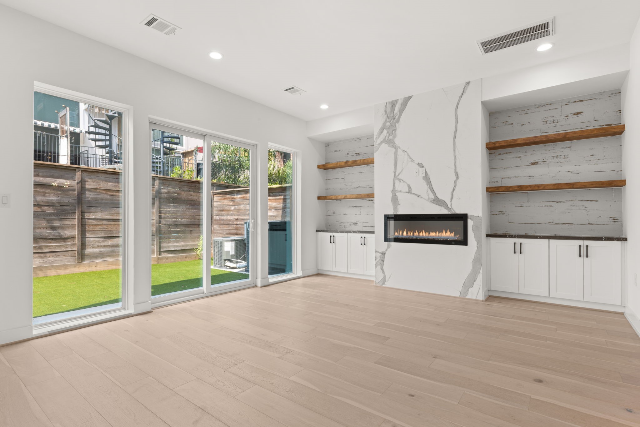 6209 Westcott Street Houston, TX 77007 - Photo 5 of 29 Expansive living room with walls of glass opening to the backyard, sleek linear fireplace, and designer built-ins with floating shelves.