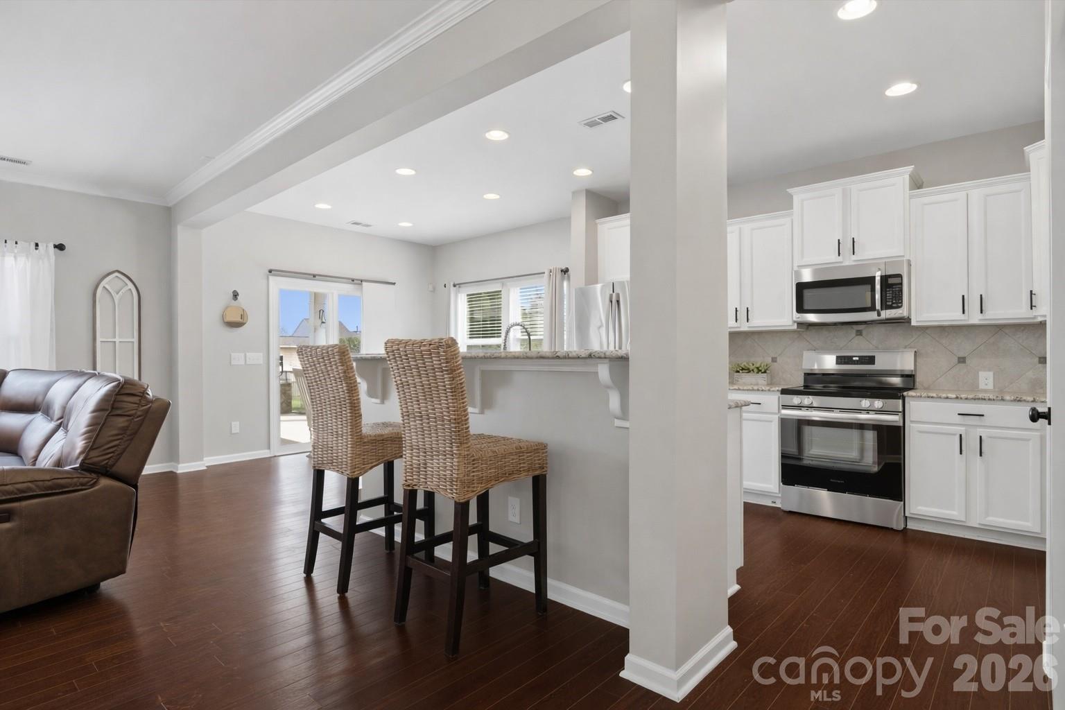 79321 Ridgehaven Road Lancaster, SC 29720 - Photo 7 of 35 a kitchen with stainless steel appliances granite countertop a stove a refrigerator a kitchen island a dining table and chairs with wooden floor