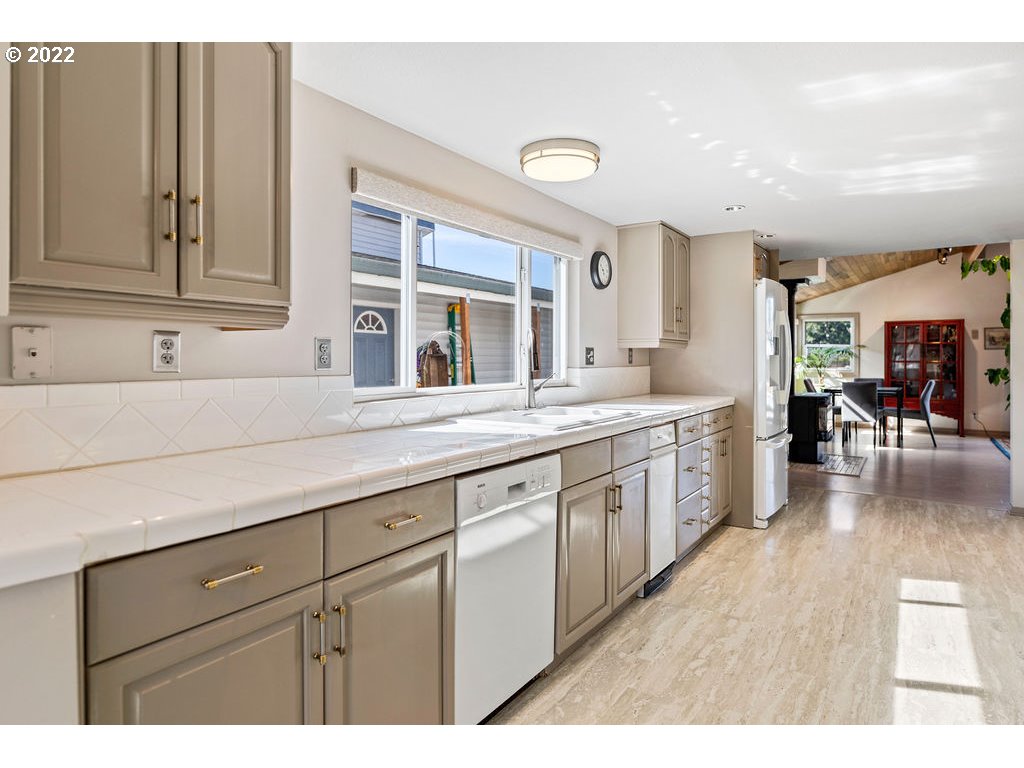 205 North Bridgeton Road, Unit W09 Portland, OR 97217 - Photo 6 of 32 a kitchen with stainless steel appliances granite countertop a sink dishwasher a stove and a dining table with wooden floor