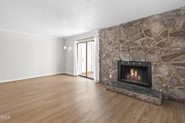 an empty room with wooden floor and fireplace