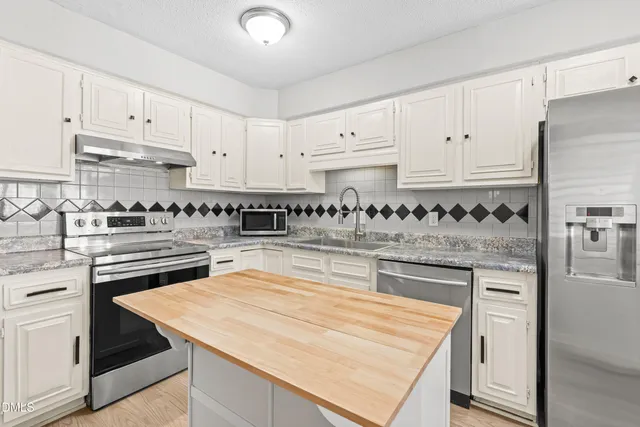 a kitchen with granite countertop white cabinets and stainless steel appliances