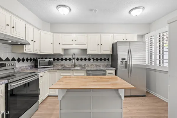 a kitchen with granite countertop white cabinets and stainless steel appliances
