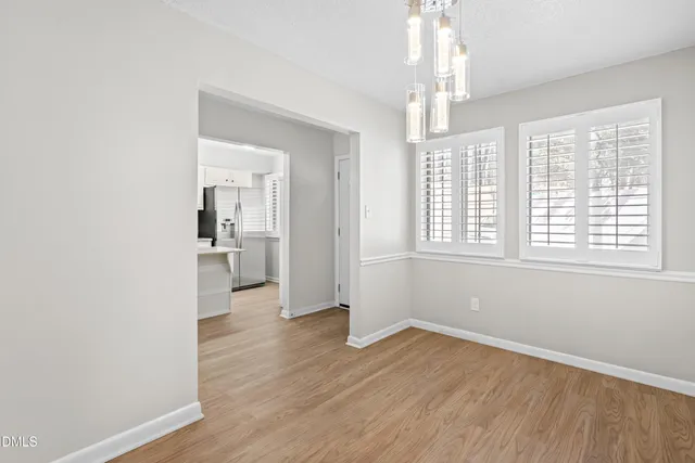 a view of an empty room with wooden floor fireplace and a window