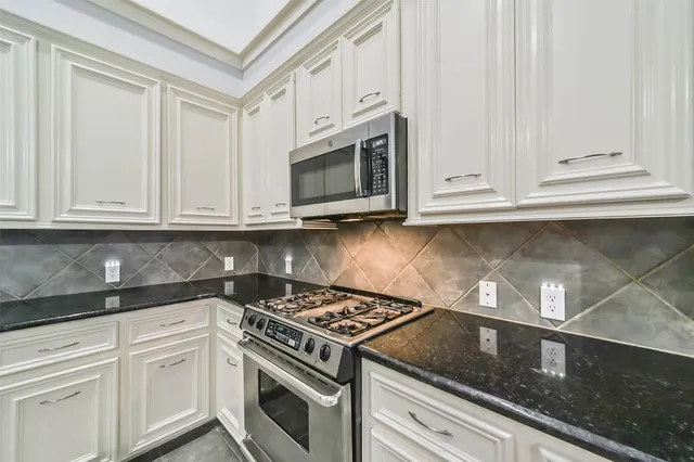 a kitchen with granite countertop white cabinets and stainless steel appliances