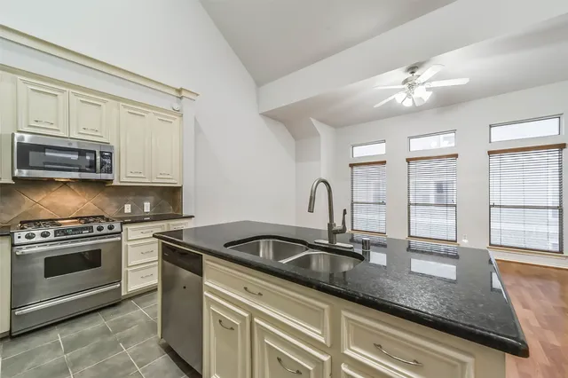 a kitchen with granite countertop a sink stainless steel appliances and cabinets