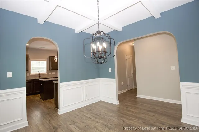 a view of a chandelier in big room with chandelier fan and windows