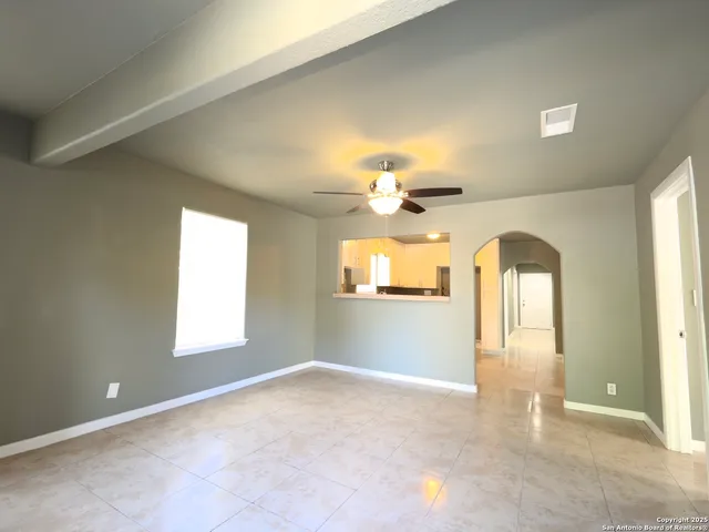 an empty room with windows and chandelier fan