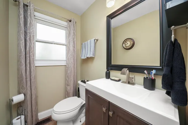 a bathroom with a toilet sink vanity and mirror