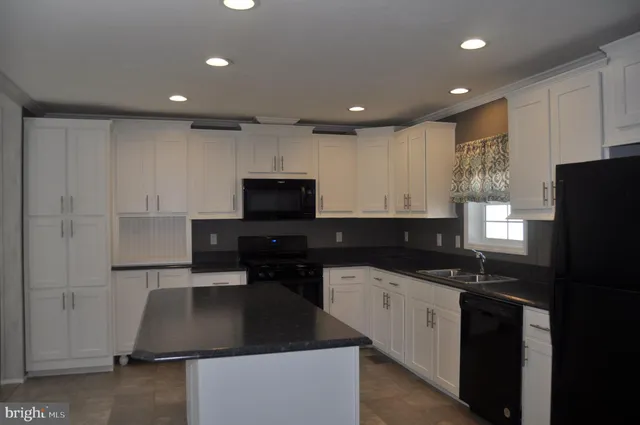 a kitchen with granite countertop a sink a counter space and cabinets