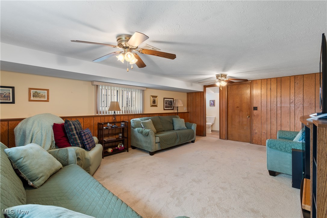 447 Center Road Bedford, OH 44146 - Photo 24 of 33 Carpeted living area featuring a textured ceiling, a ceiling fan, and wooden walls