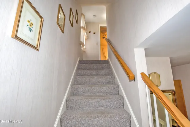 a view of staircase with lots of frames on wall and a window